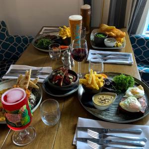 a wooden table with plates of food and glasses of wine at The Kings Head Inn, Home of The Acle Steak in Acle +9 photos