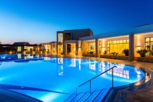 a large swimming pool in front of a building at night at Grand Hotel Holiday Resort in Hersonissos