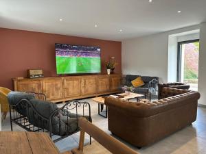 a living room with couches and a flat screen tv at Entre St Malo et Rennes, grande maison 12 couchages Chez Yvonne in Irodouër