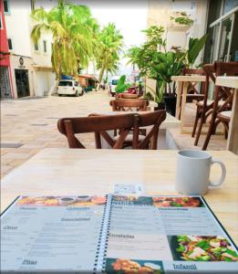 a book on a table with a cup of coffee at Hostal del Mar in Playa del Carmen +2 photos