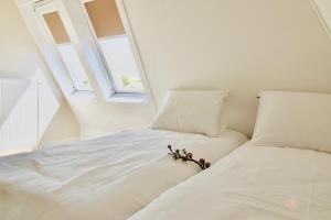Una cama blanca con flores en una habitación. en Vakantiehuis Noordwijk, en Noordwijk 43 fotos más