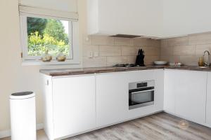 Una cocina blanca con gabinetes blancos y una ventana. en Vakantiehuis Noordwijk, en Noordwijk