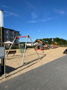a playground with a swing set in the sand at MB Apartments z Basenem i Ogrodem in Sarbinowo +11 photos