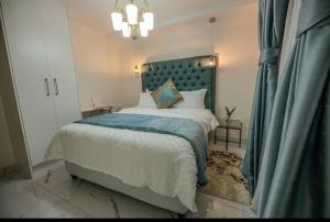 Un dormitorio con una cama grande con cabecero azul. en Guest On 97, en Gaborone
