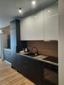 a kitchen with black and white cabinets and a sink at LOCUS SKY TOWER Katowice in Katowice