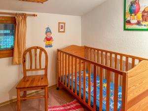 a nursery with a crib and a wooden chair at Ferienwohnung Haus Rosenbichl GbR in Schönau am Königssee