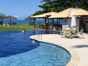 a swimming pool with a table and chairs and the ocean at Paraíso dos corais Pe na areia in Guarajuba