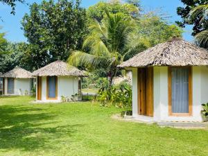 two bungalows with thatched roofs in a yard at Madasari Village in Madasari