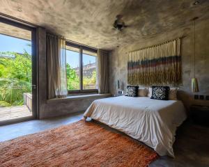 a bedroom with a large bed and a large window at Nomade Tulum in Tulum
