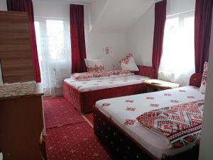 a bedroom with two beds with red and white sheets at Casa Emilia in Vatra Dornei