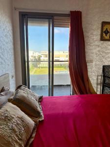 a bedroom with a pink bed and a large window at Appartement moderne à Puerto Banus in Mansouria