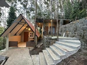 a house in the woods with a stone wall at 100 Oaks Estate in Yercaud