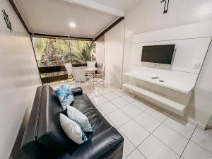 a living room with a couch and a tv at Flat com 1 quarto com ar split, sala e cozinha completa, No condomínio Portal do Atlântico a 100m praia de Taperapuã (Barraca do Gaúcho) , portaria 24hrs, piscina. in Coroa Vermelha