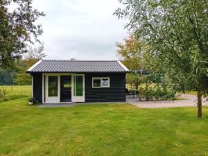 WijnjewoudeB&B Stripsein的一座带草地庭院的黑色小房子