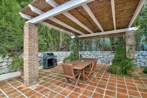 patio z drewnianym stołem i kamienną ścianą w obiekcie Villa Atréju w mieście Cómpeta