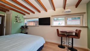 a bedroom with a bed and a table and a window at The Shed in De Cocksdorp