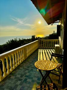 a wooden bench sitting on a balcony with the sunset at Traditional old house in Dhërmi +7 photos