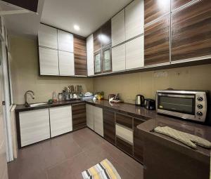 a kitchen with wooden cabinets and a microwave at Saramega Homestay in Butterworth +4 photos