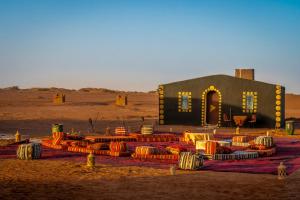 a building in the middle of a desert withools in front of it at Sahara Sunset Camp M'hamid in Mhamid