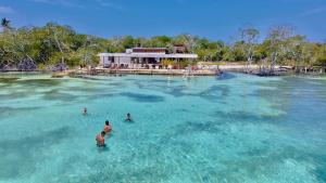 un gruppo di persone in acqua vicino a una casa di Medusa Hostel Isla Tintipan a Tintipan Island