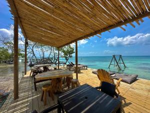 una terrazza in legno con tavoli e sedie sulla spiaggia di Medusa Hostel Isla Tintipan a Tintipan Island