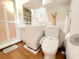 une salle de bain blanche avec toilettes et lavabo dans l'établissement Shinjuku NZO Apt, à Tokyo 2 autres photos
