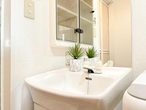 une salle de bain blanche avec un lavabo et un miroir dans l'établissement Shinjuku NZO Apt, à Tokyo