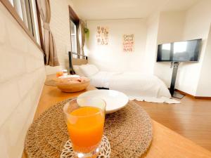 un verre de jus d'orange assis sur une table dans une pièce dans l'établissement Shinjuku NZO Apt, à Tokyo