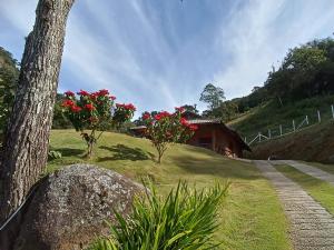 a house on a hill with red flowers in a yard at Chalé da Sorte in Gonçalves