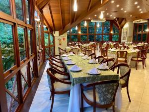 una sala da pranzo con tavoli, sedie e finestre di Hotel Águas Claras a Santa Cruz do Sul
