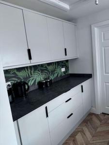 a kitchen with white cabinets and a black counter top at Blessed Princess House With Free Parking in Sunderland +18 photos