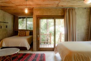 a bedroom with two beds and a sliding glass door at Nomade Tulum in Tulum