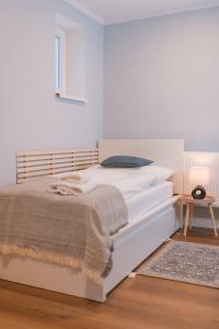 a white bed in a white room with a table at Blue City apartments in Trenčín