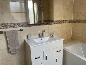 a bathroom with a sink and a mirror and a tub at 3 Bed House - Sleeps 5 - Garden - Parking - Wifi in Dartford