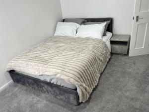 a bed with a blanket and pillows in a room at 3 Bed House - Sleeps 5 - Garden - Parking - Wifi in Dartford