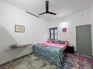 a bedroom with a bed and a ceiling fan at Flamingos villa - by Bodhi garden in Varkala