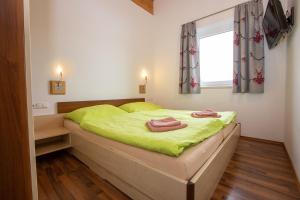 a bedroom with a bed with green sheets and a window at Chalet Central Top CC 7 in Königsleiten