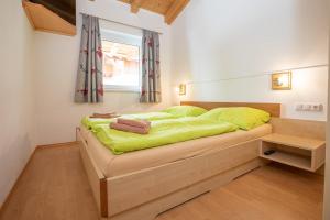 a bedroom with a bed with green sheets and a window at Chalet Central Top CC 7 in Königsleiten