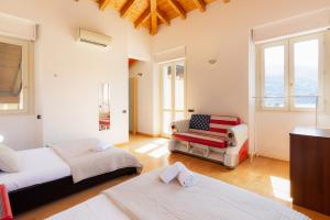 a bedroom with two beds and a chair and windows at Luxury Villa Laglio in Laglio +75 photos
