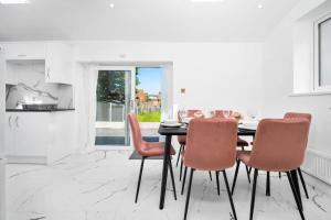 a dining room with a black table and pink chairs at Family Contractors 3 bed house free parking sleeps7 in Bilston
