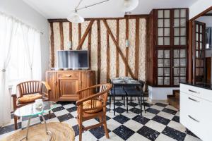 Una sala de estar con televisión, mesa y sillas. en Appartement authentique à colombage 15mn de Disney, en Ferrières-en-Brie