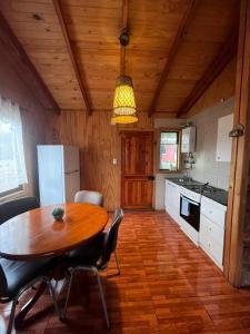 a kitchen with a wooden table and a wooden floor at Cabañas Rukaparra in Pinto