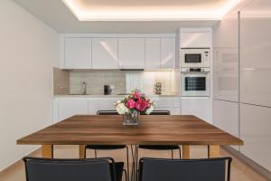 a kitchen with a wooden table with a vase of flowers at Grand Horizon Luxury Boutique Apartments in Puerto Rico de Gran Canaria