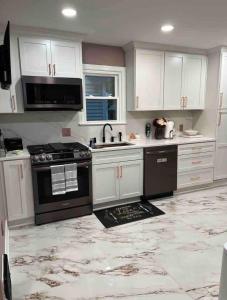 a kitchen with white cabinets and a black stove at Elevated Entertainment Sleep Suite in Cleveland +8 photos