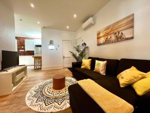 a living room with a black couch and a television at Le 224 - Appartements Pura Vida in Quebec City