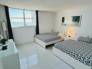 Una habitación blanca con dos camas y una ventana. en The Tides Condo on Hollywood, en Hollywood 268 fotos más