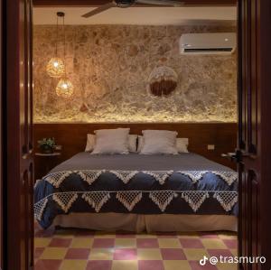 a bedroom with a bed and a stone wall at Itinerante/Casa del Mago. Mérida in Mérida