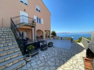 a house with stairs and a balcony next to the water at Apartments Mediterano in Senj
