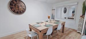 a dining room table with chairs and a large clock on the wall at Kaylee Lounge in Le Mans