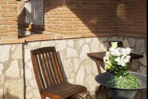 a chair and a vase of flowers next to a brick wall at Telemann - Xeckin Holidays in El Vendrell